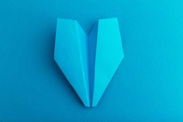 Flat lay of a paper plane on pastel blue color 