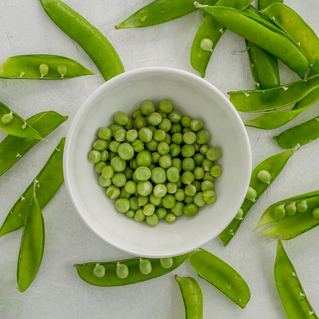 Flat lay peas in bowl with pods