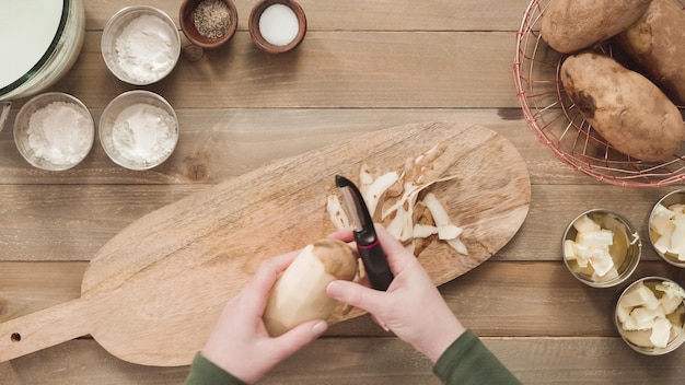 Flat lay. Peeling organic yellow potatoes with potato peeler.