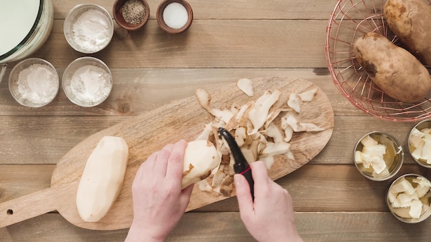 Flat lay. Peeling organic yellow potatoes with potato peeler.