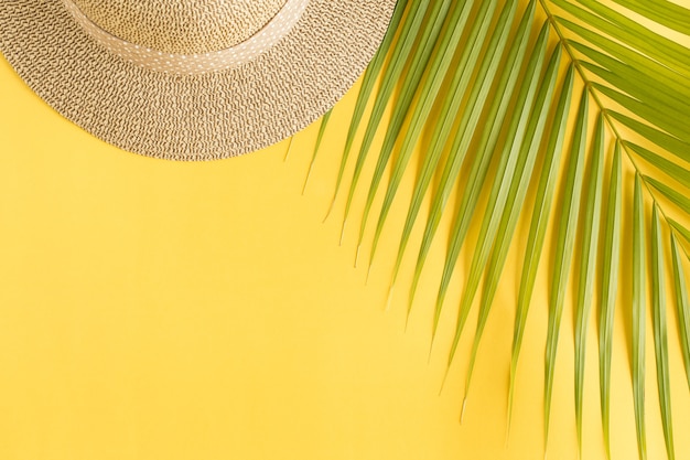 Flat lay photo coconut leaf and hat on yellow background