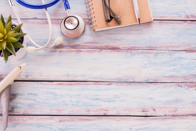 Flat lay photo with blank notebookglassesairplane modelflower pen and blue stethoscope