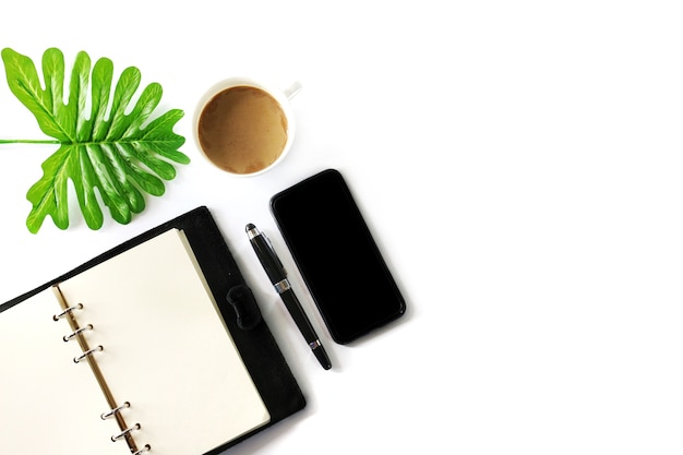 flat lay photo with notebook, smartphone, pen, coffee cup and tropical leave 