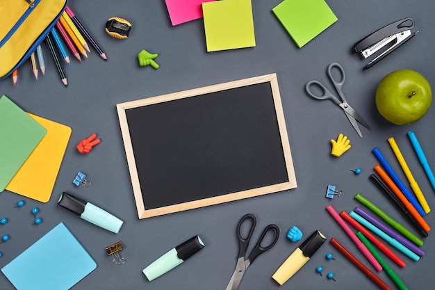 Foto piatta della scrivania dell'area di lavoro con accessori per la scuola o forniture per ufficio su sfondo grigio