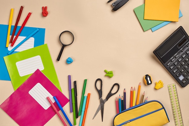 Flat lay photo of workspace desk with school accessories or office supplies on pink background