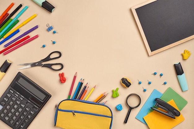 Foto piatta della scrivania dell'area di lavoro con accessori per la scuola o forniture per ufficio su sfondo rosa