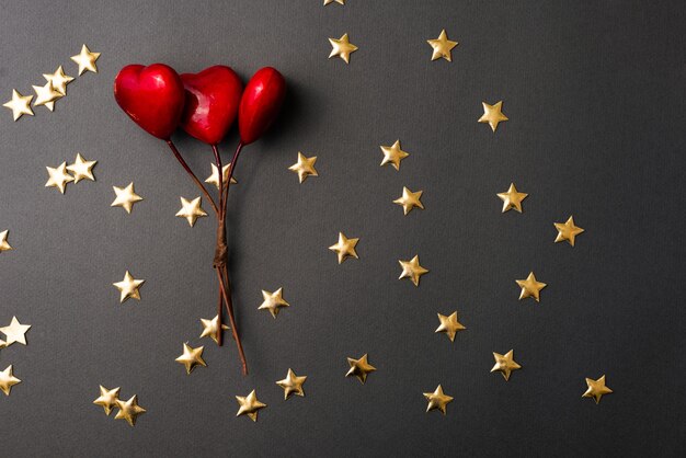 Flat lay photo of yellow stars and red hearts over black table