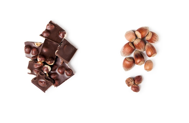 Flat lay of pieces of dark chocolate with whole nuts.