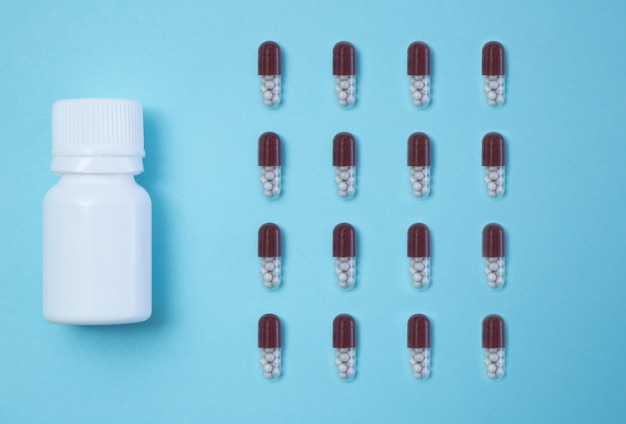 Flat lay of a pill bottle and four rows of capsules near