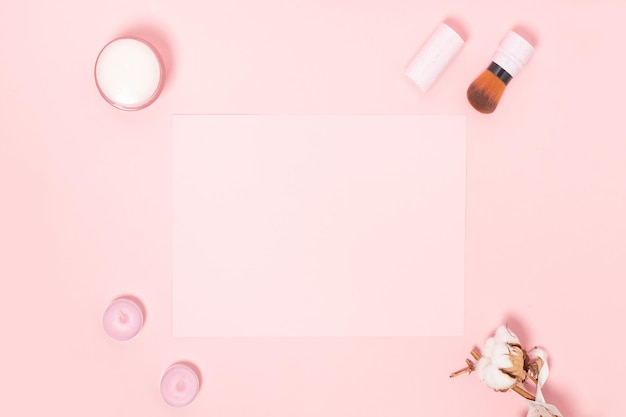 Flat lay pink composition with empty note cosmetics makeup tools isolated on a pink background