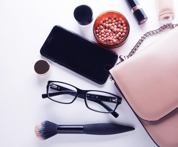 Flat lay of pink leather woman bag open out with cosmetics acce