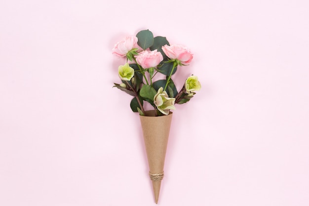 Flat lay of pink rose flowers in a eco paper cornet isolated