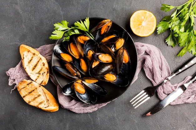 Photo flat-lay plate of cooked mussels and cutlery