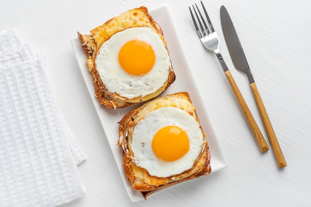 Flat lay of plate with French Croque Madame sandwiches made with ham and cheese and fried egg