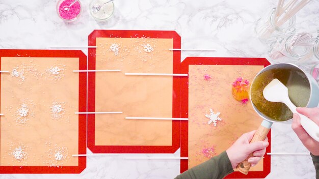 Flat lay. Pouring caramelized sugar on silicone mats to make homemade lollipops.