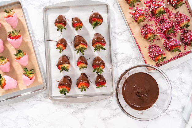 Flat lay. Preparing chocolate covered strawberries on a cookie tray.