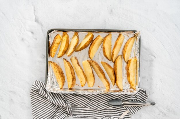 Flat lay Preparing russet potatoes in wedges with olive oil and spices to bake in the oven