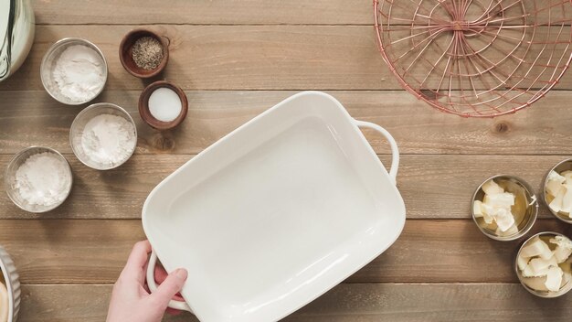 Flat lay. Preparing scalloped potatoes in a white ceramic baking dish.