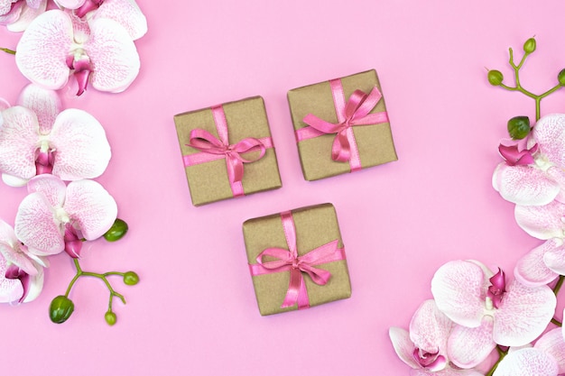 Flat lay of present boxes with pink ribbon and orchid flowers