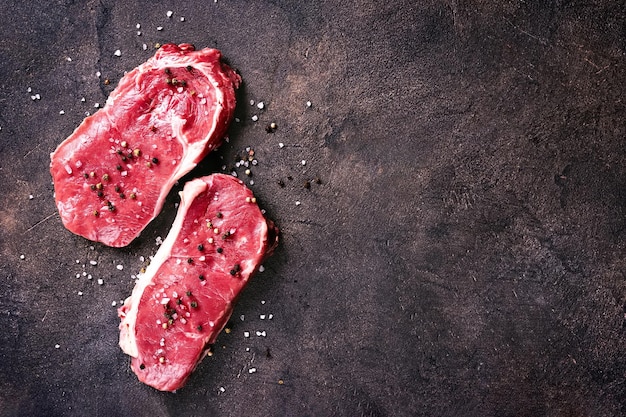 Flat lay of raw beaf steaks on dark background Copy spyce