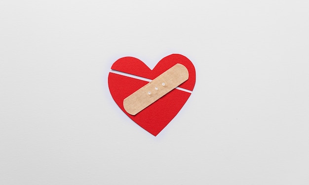 Flat lay red broken heart with band aid