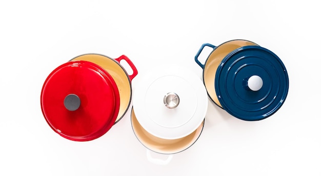 Flat lay. Red, white and blue enameled cast iron covered round dutch ovens on a whjite background.