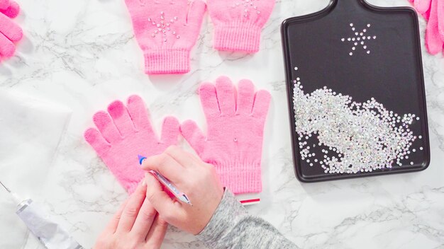 Flat lay. Rhinestone pink kids gloves with snowflake shapes.