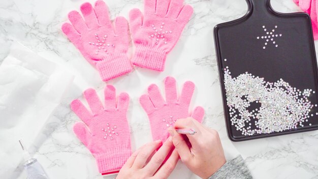 Flat lay. Rhinestone pink kids gloves with snowflake shapes.