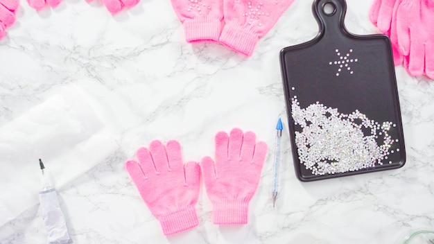 Flat lay. Rhinestone pink kids gloves with snowflake shapes.