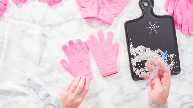 Flat lay. Rhinestone pink kids gloves with snowflake shapes.