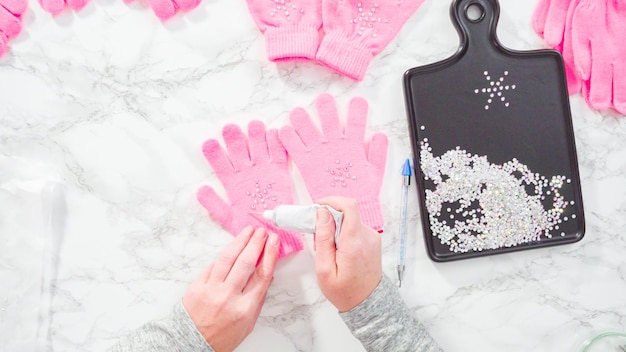 Flat lay. Rhinestone pink kids gloves with snowflake shapes.