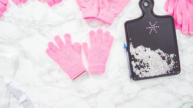 Flat lay. Rhinestone pink kids gloves with snowflake shapes.