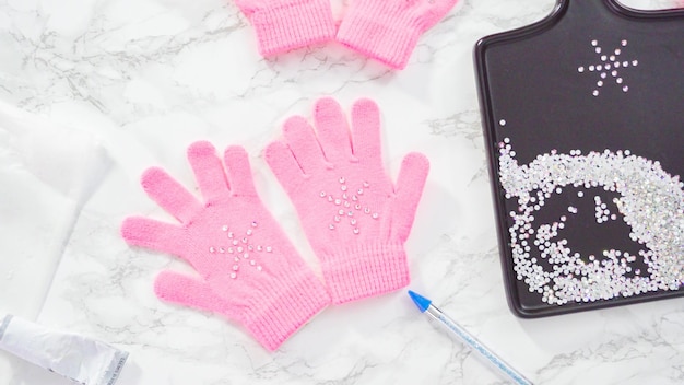 Disposizione piatta. guanti rosa per bambini con strass a forma di fiocco di neve.