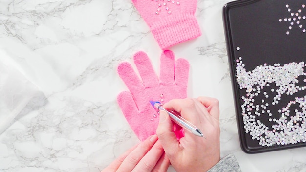 Flat lay. Rhinestone pink kids gloves with snowflake shapes.
