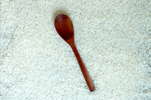 Foto strato piatto di grano di riso con cucchiaio di legno marrone vista dall'alto