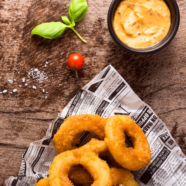 Photo flat lay of ring fries on newspaper with mustard