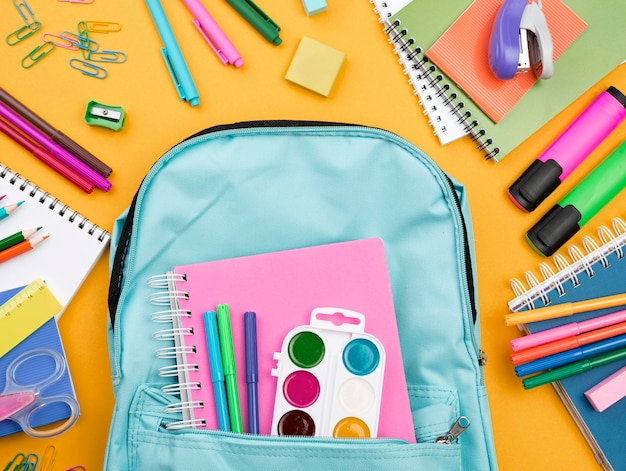 Flat lay of school essentials with backpack and colorful pencils