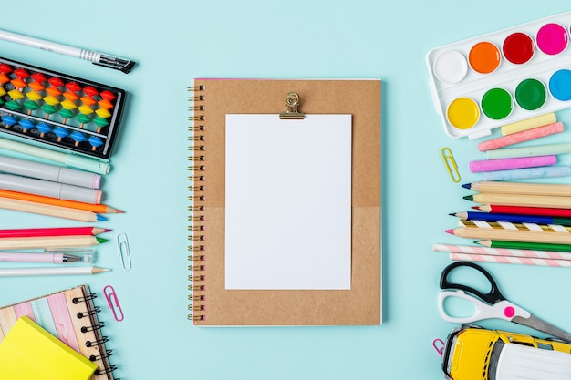 Photo flat lay of school supplies on table around empty space for text.