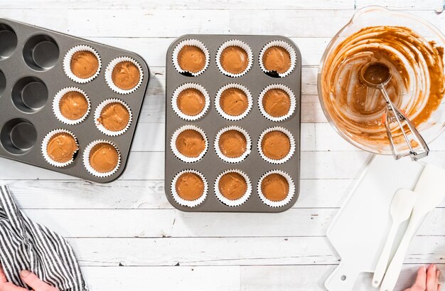 Flat lay. Scooping dough into the foil cupcake liners to bake chocolate raspberry cupcakes.