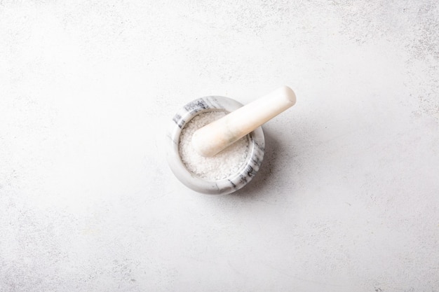 Photo flat lay of sea salt on marble mortar. skin and self-care concept, top view.