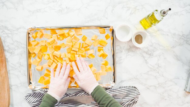 Flat lay. Seasoning butternut squash with oil, salt, and pepper for roasting in the oven.