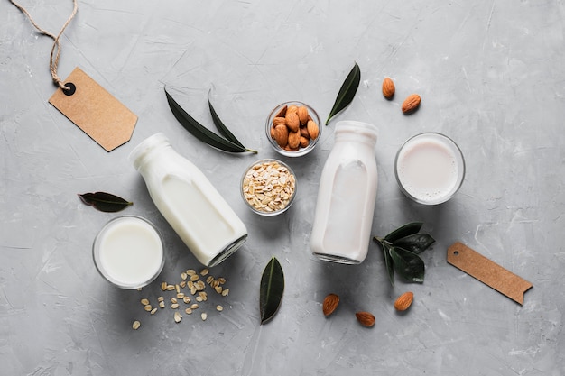 Flat lay set of milk bottles and glasses with oatmeal and almonds