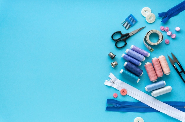 Flat lay of sewing accessories. threads and tailoring tools on blue