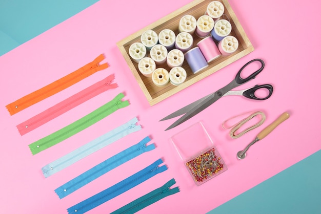 Flat lay of sewing material contains the fabrics, scissors, zipper and thread rolls.