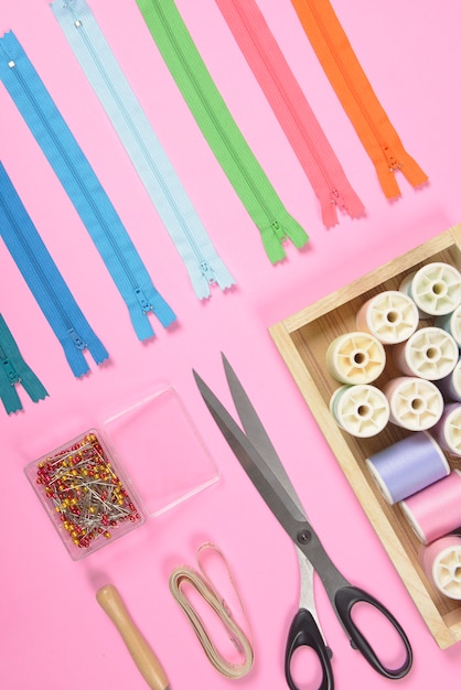 Flat lay of sewing material contains the fabrics, scissors, zipper and thread rolls.