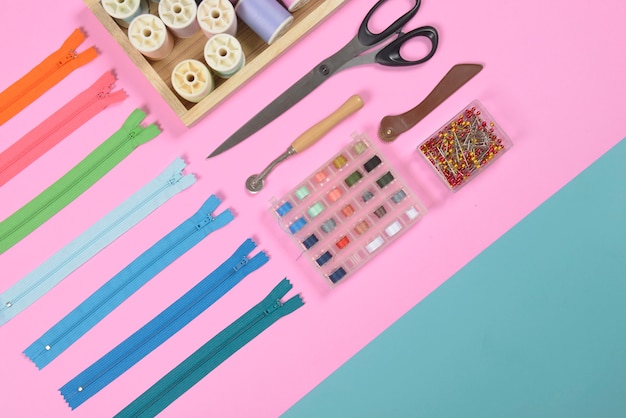 Photo flat lay of sewing material contains the scissors, measure tape, zipper and thread rolls.