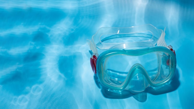 Flat lay shot of blue diving mask over turquoise blue background minimalist photo of dive mask