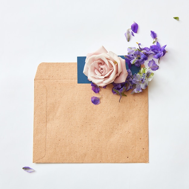 Flat lay shot of flowers and eco paper envelope on white background