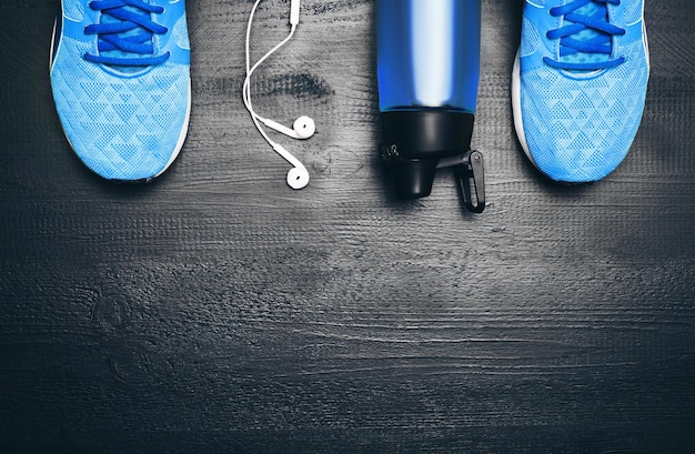 Flat lay shot of Sport equipment Sneakers water earphones and phone on wooden background