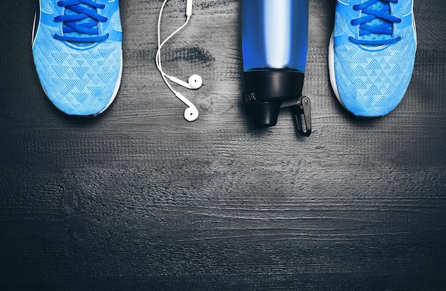 Flat lay shot of sport equipment sneakers water earphones and
phone on wooden background